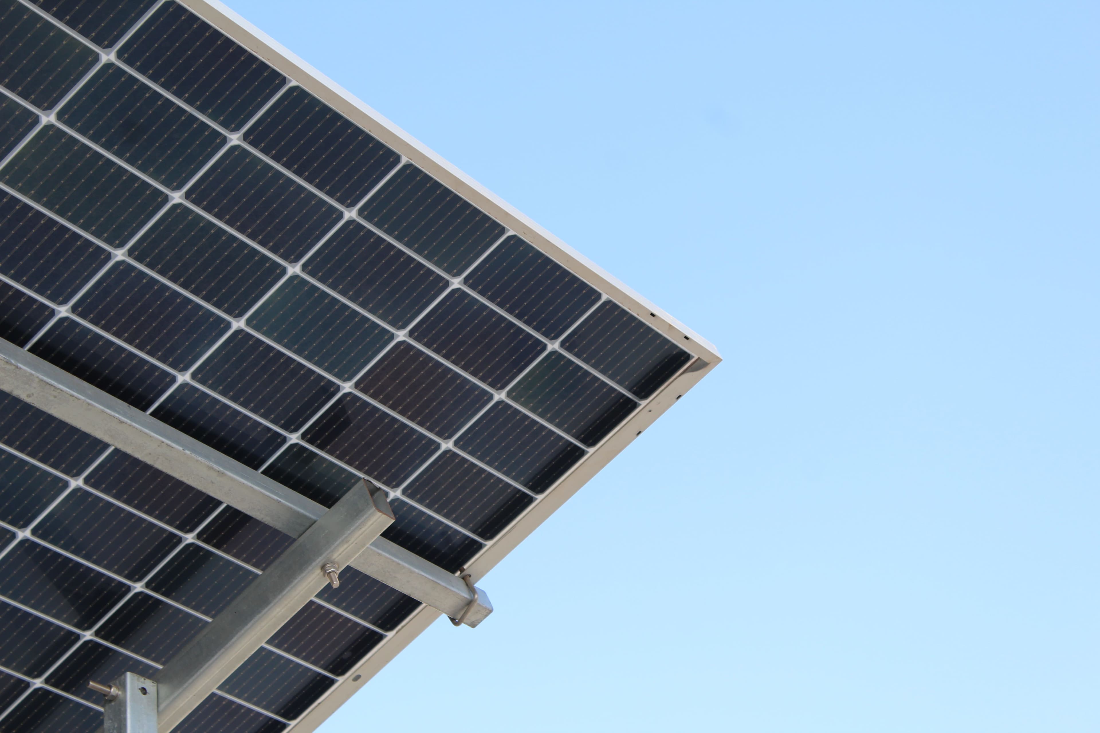 Close-up of a solar panel and its mounting structure against a clear sky